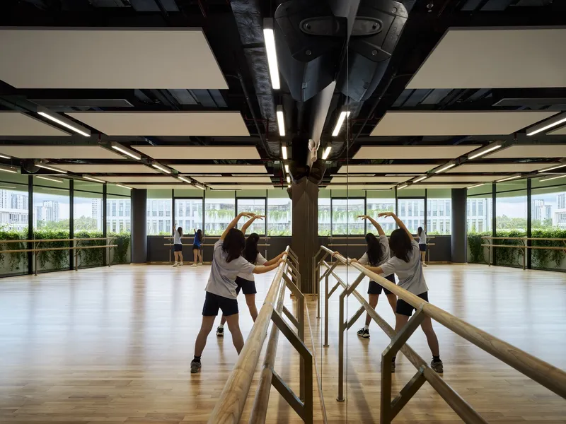 Dance studio with timber barre along mirrored column and exposed black ceiling infrastructure