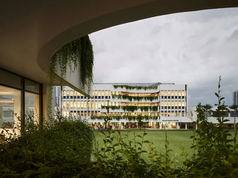 View through curved soffit with hanging vines toward the planted lawn at twilight
