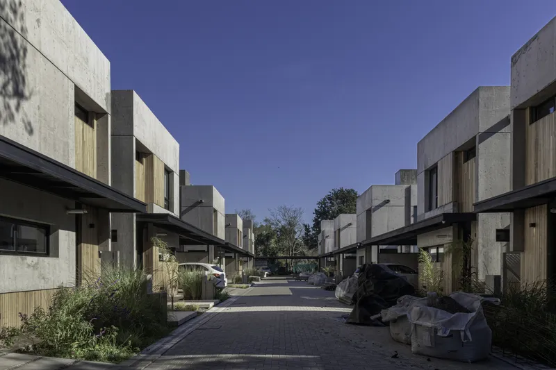 View down the communal paved street with concrete volumes stepping back on both sides