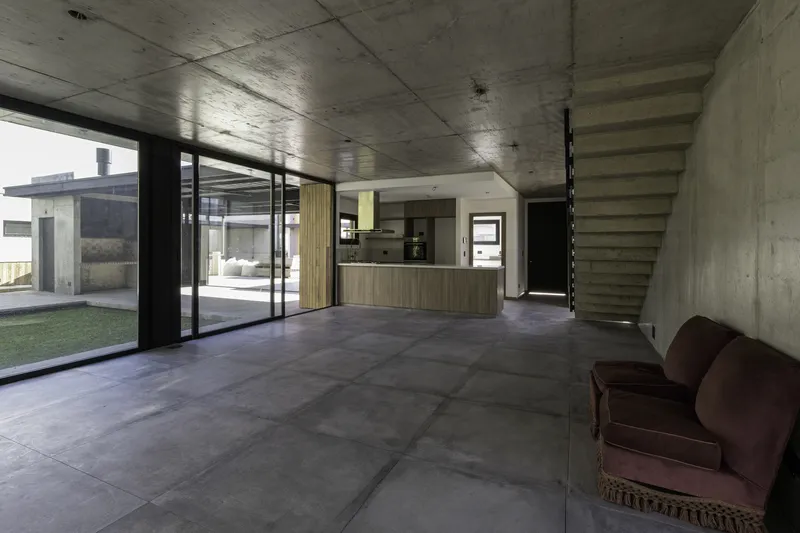 Open-plan interior with exposed concrete ceiling and kitchen island viewed from the living area