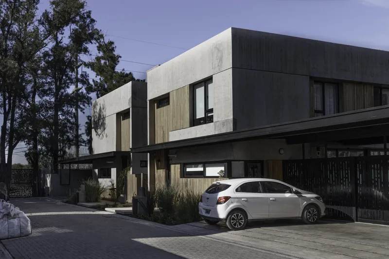 Street facade combining board-formed concrete panels and vertical timber screening at dusk