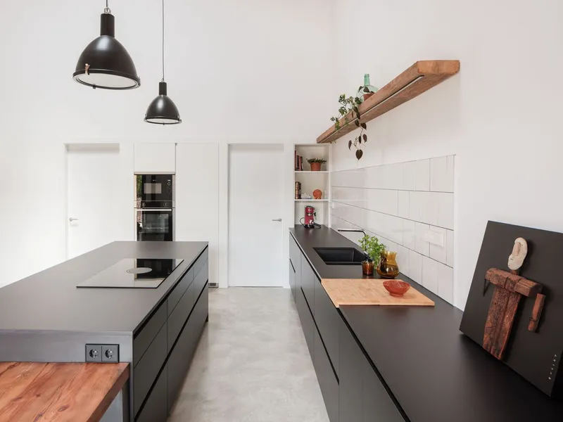 Kitchen with matte black island and cabinetry, white subway tile backsplash, and polished concrete floor under pendant lights