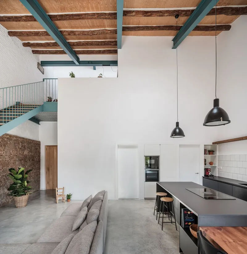 Open-plan kitchen and living space with exposed timber joists supported by turquoise steel beams overhead