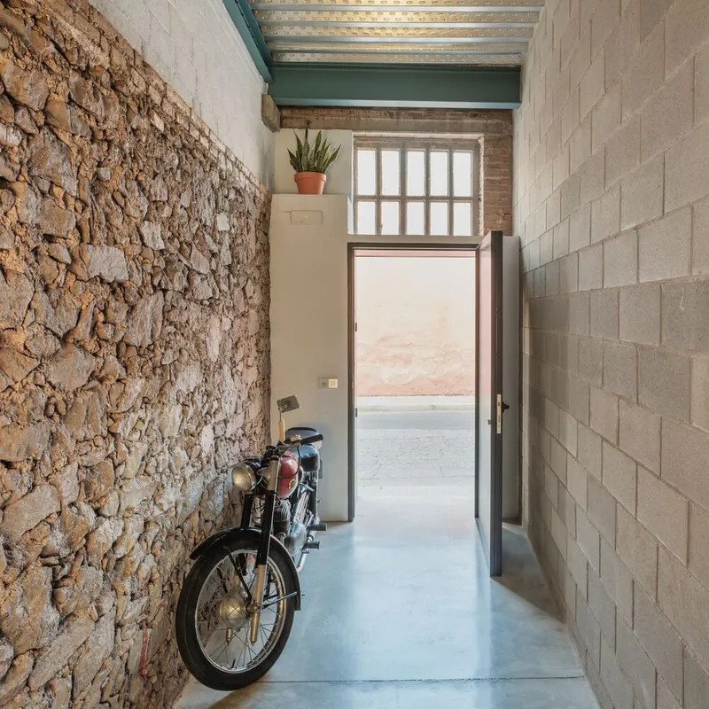 Narrow entry hall with exposed stone wall on one side and concrete block on the other