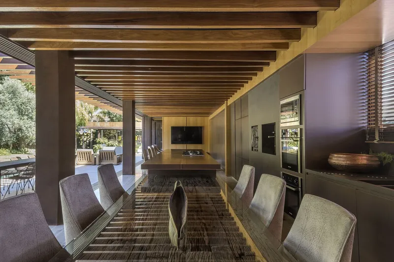 Open-plan living area with timber beam ceiling and pool terrace visible through corner opening
