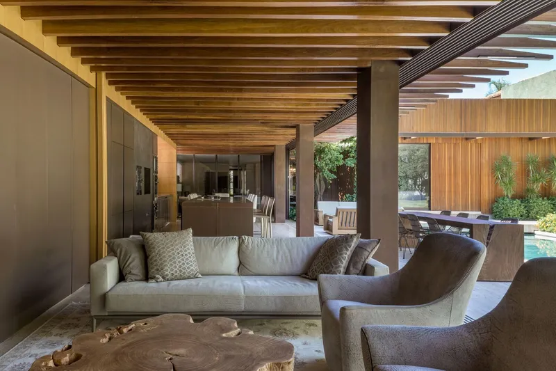 Open living area with slatted timber ceiling beams extending toward the poolside terrace and garden