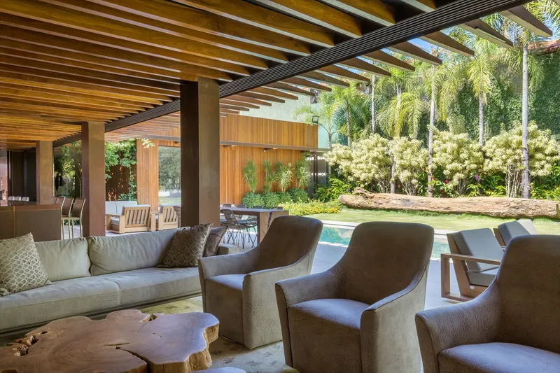 Covered terrace framing the garden with flowering shrubs and palm trees under afternoon sun