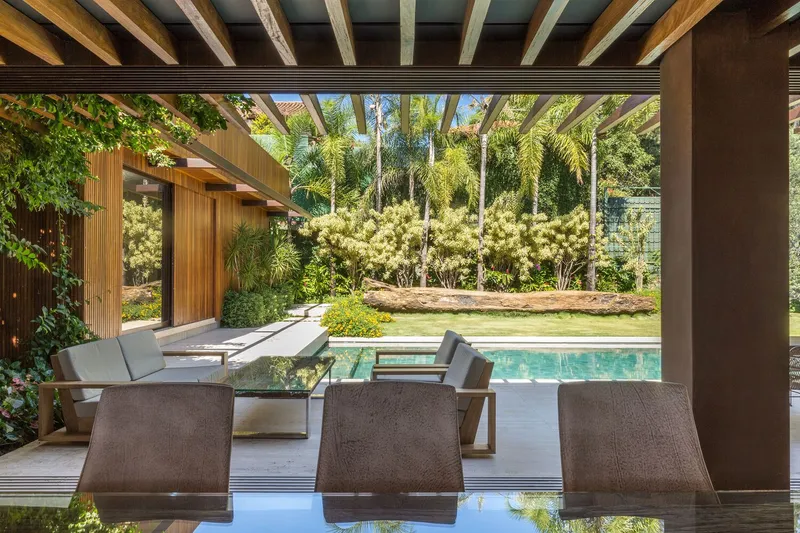 Timber-beamed pergola opening to the pool and landscaped lawn beyond