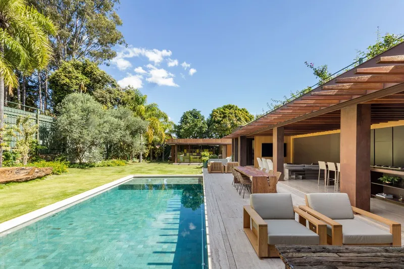 Poolside deck with timber lounge seating overlooking the lawn and timber pavilion