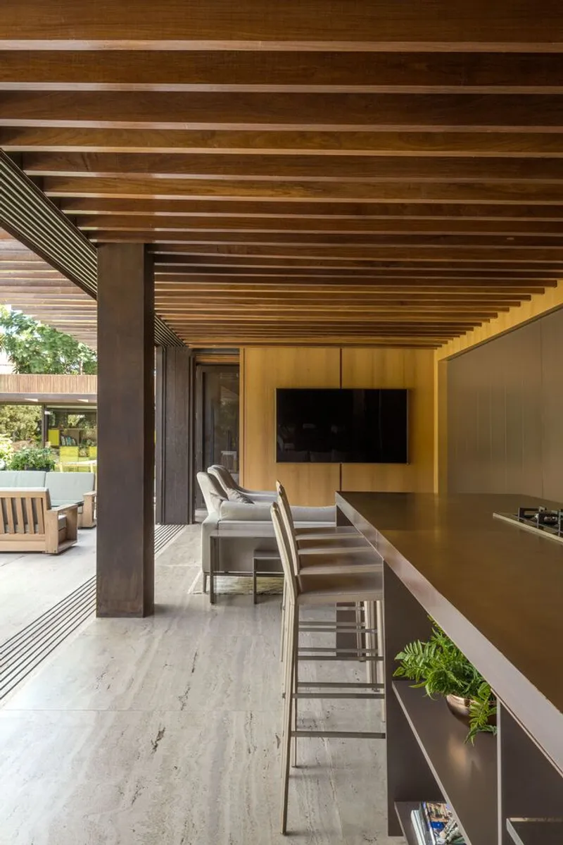 Interior view beneath the parallel timber slat ceiling with bar seating and garden beyond