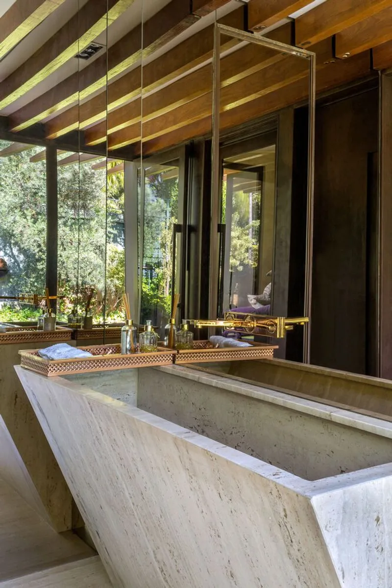 Travertine vanity beneath perforated brass mirrors suspended from the timber ceiling structure