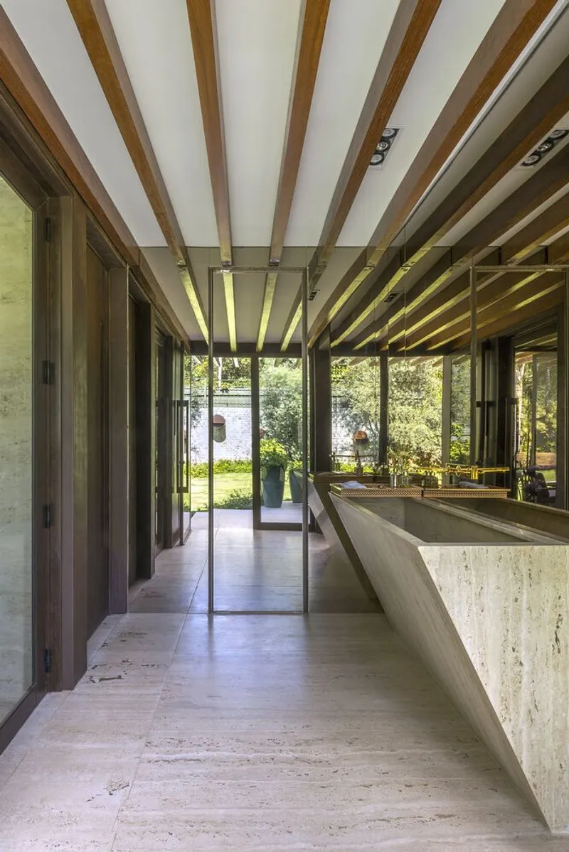 Interior corridor with travertine flooring and timber beam ceiling looking toward glazed garden doors