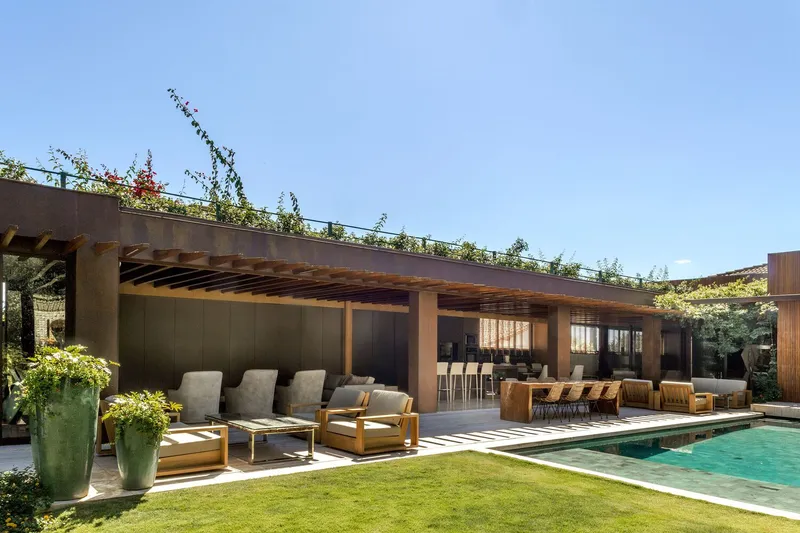 Pool terrace beneath planted green roof with timber columns and rafters shading seating areas