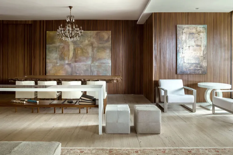 Living room with vertical timber slat walls flanking abstract paintings and a crystal chandelier overhead