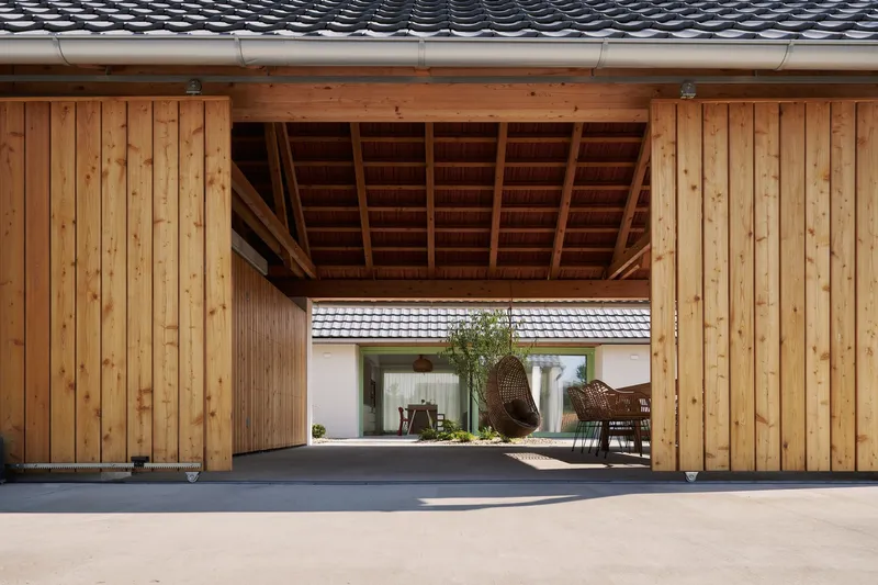 Covered courtyard with vertical timber cladding and exposed beam ceiling framing a view through to the garden