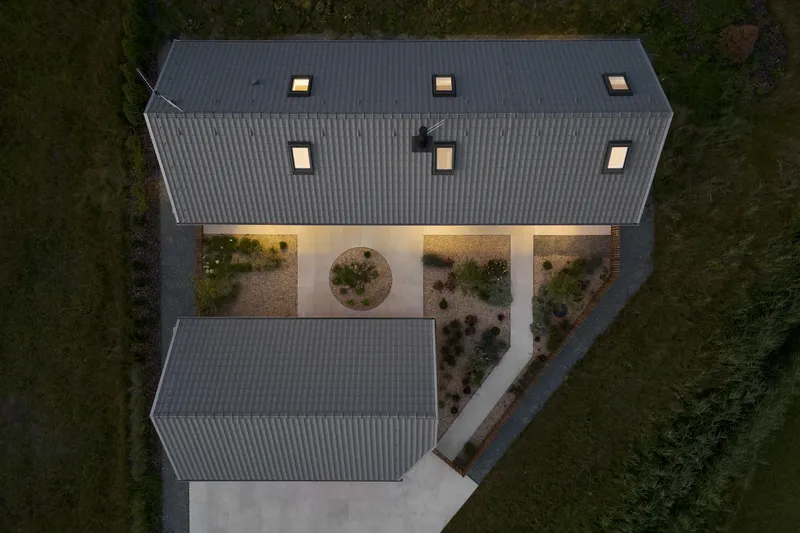 Drone view of the tiled roofs and illuminated courtyard with circular planting bed at dusk