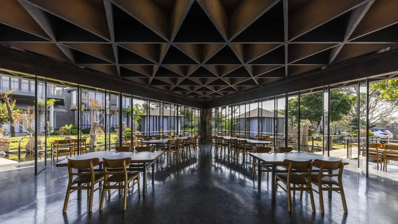 Dining room interior with coffered ceiling grid and floor-to-ceiling glazing overlooking the landscaped garden