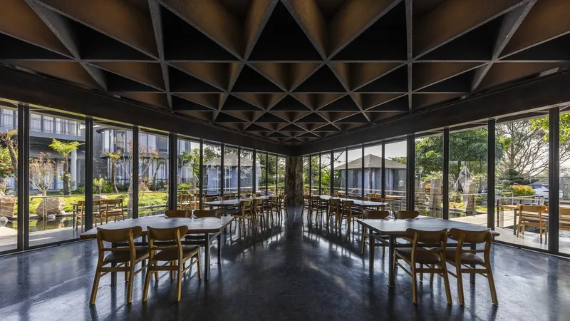 Interior dining space with geometric coffered ceiling and full-height glazing overlooking the garden and pond