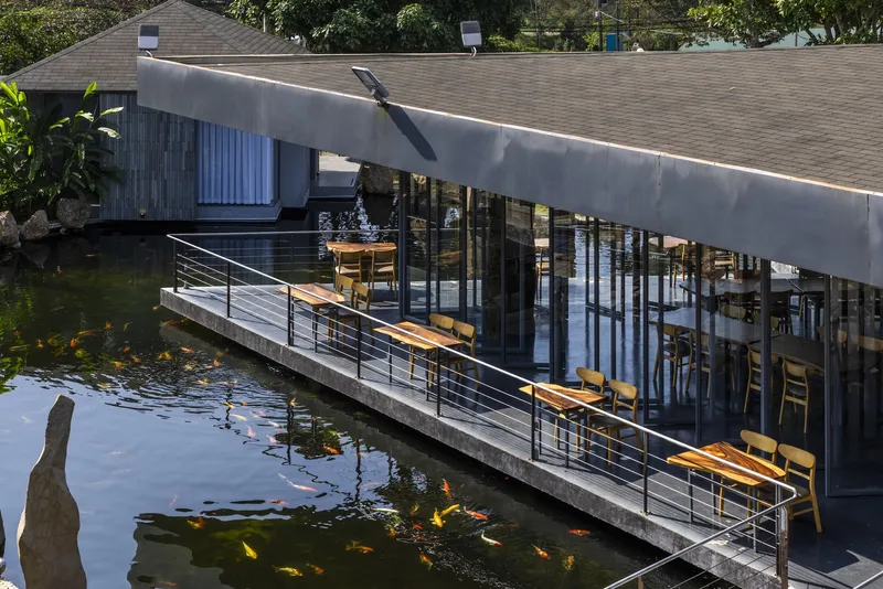 Concrete deck with benches and tables cantilevered over a koi pond filled with orange fish
