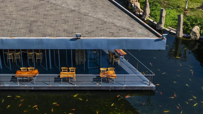 Aerial view of the cantilevered terrace with yellow furniture suspended over a koi pond