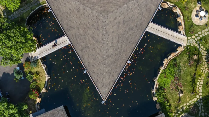 Drone view of the triangular courtyard roof framed by two water-filled wings with koi