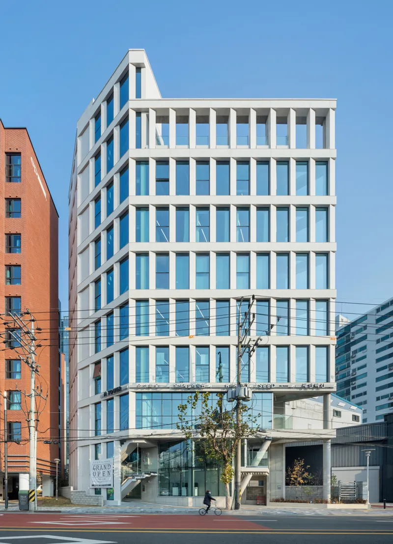 Street view of the white vertical sunshade facade with a cyclist passing near the entrance