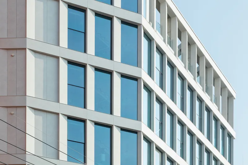 Detail of the facade showing horizontal white mullions separating vertical bands of glazing and panels