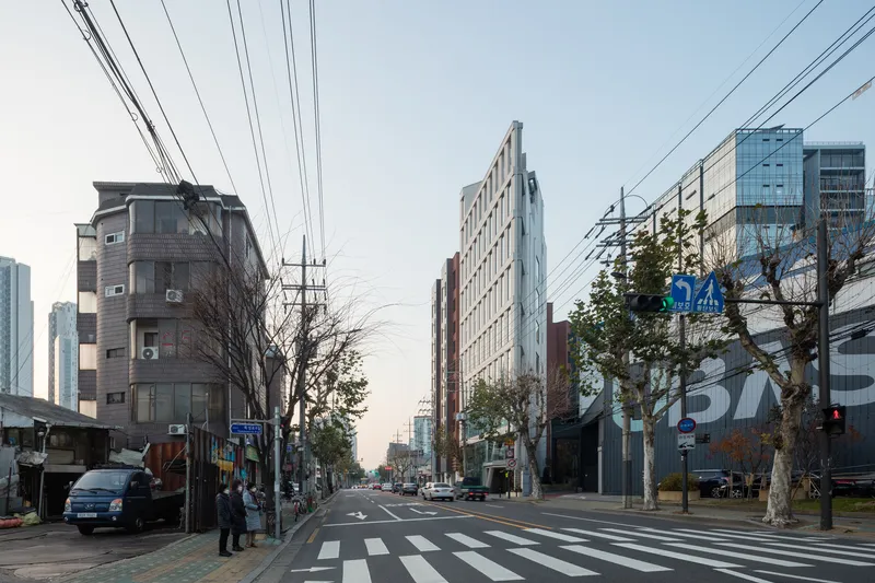 Street view at dusk showing the white facade framed by overhead power lines and bare trees