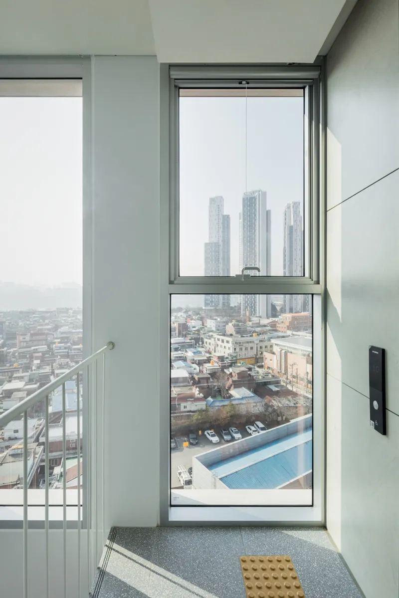 Elevator lobby with floor-to-ceiling window overlooking the rooftop pool and distant towers in haze