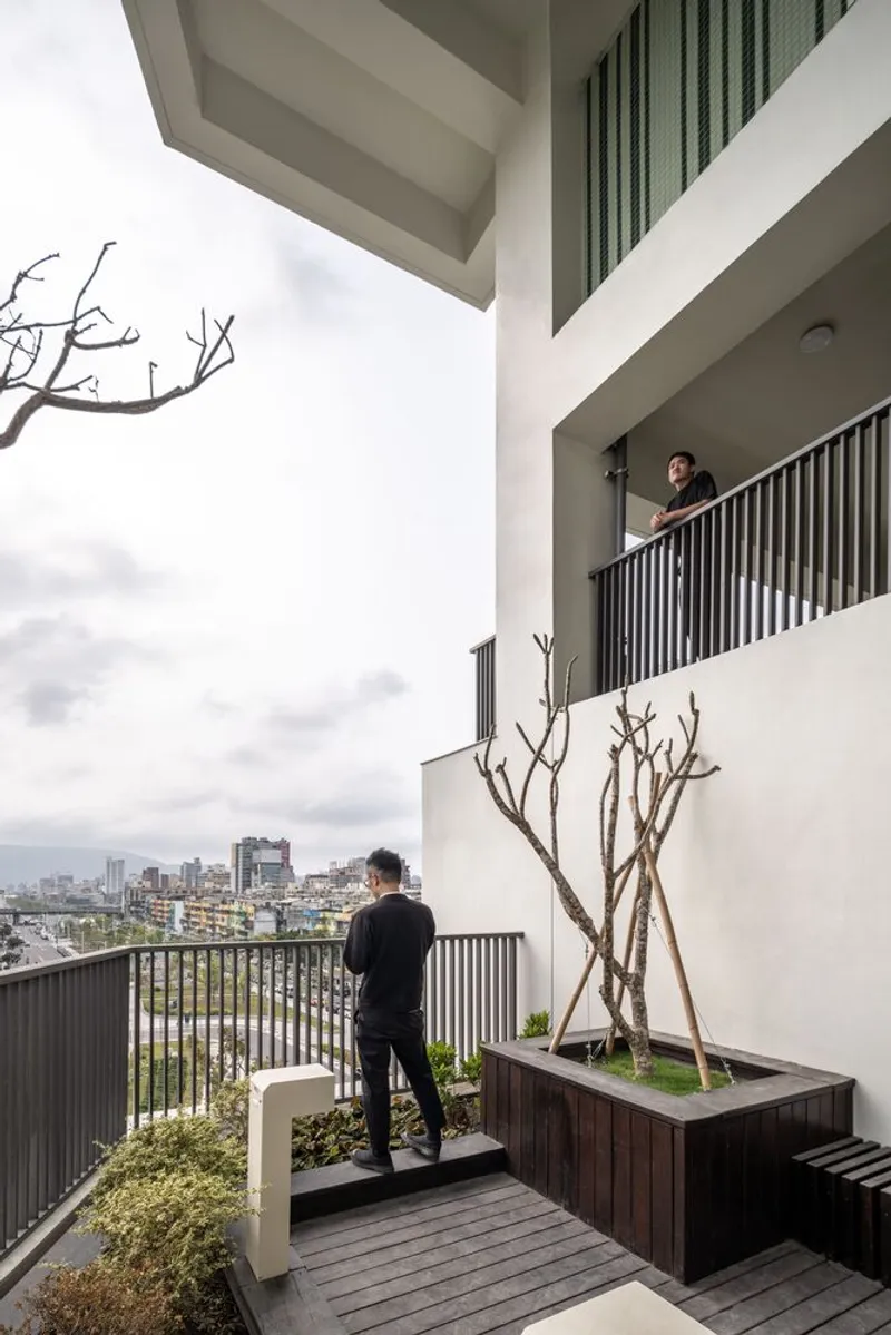 Two residents on stacked outdoor terraces with timber planters and bare branched trees