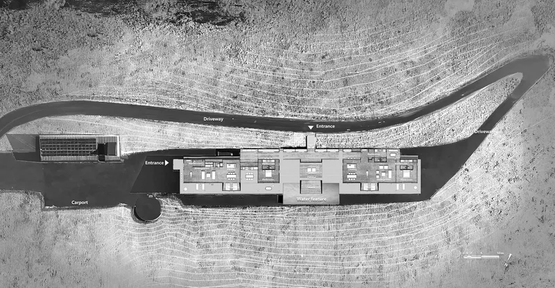 Overhead view showing the floor plan with entrance canopy and carport amid tire tracks in dried grass