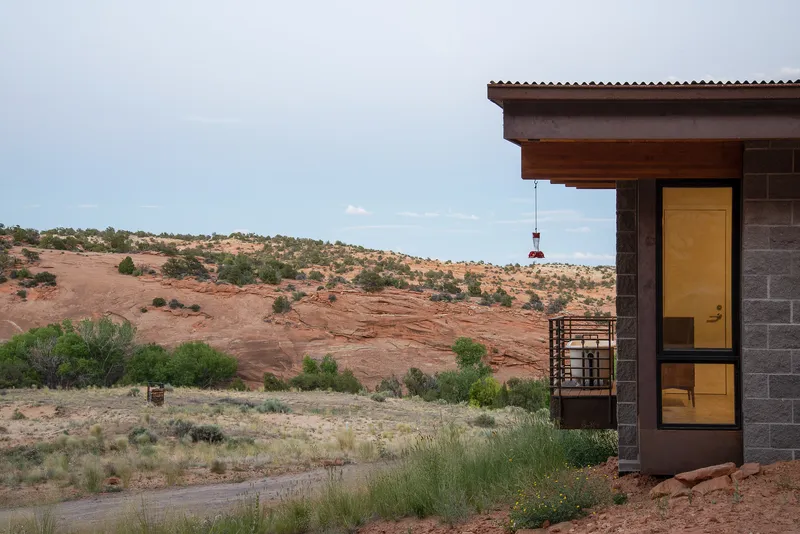 Corner of the concrete block and timber facade with glazed doors opening to the desert landscape