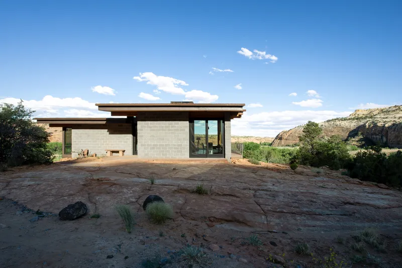 Front elevation showing concrete block walls and timber soffits on a red sandstone outcrop under blue sky