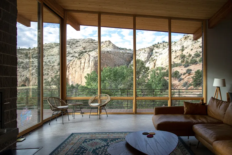 Living room with floor-to-ceiling glazing framing views of eroded sandstone cliffs and native vegetation