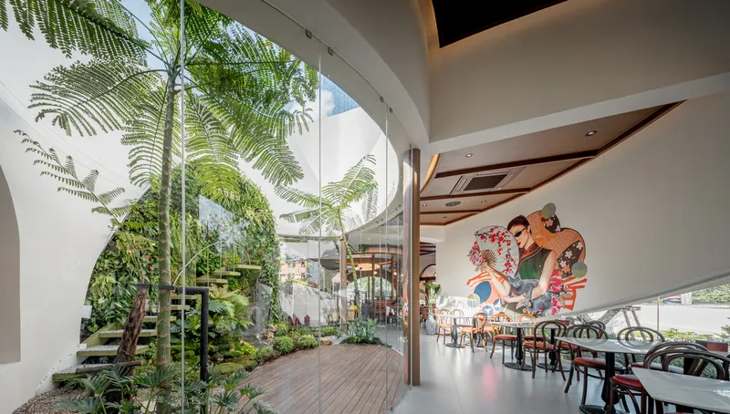 Dining area with mural and view to courtyard planted with ferns under curved white walls