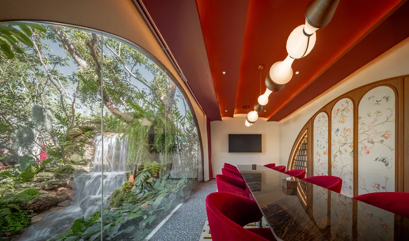 Interior lounge with red seating facing a glazed waterfall wall beneath a red slatted ceiling