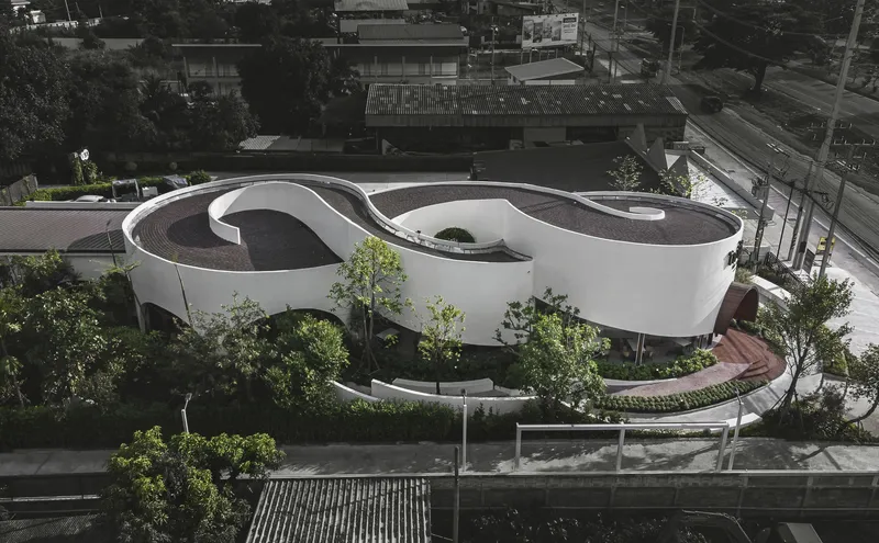 Elevated view of the cloverleaf roof set among trees along a street at dusk