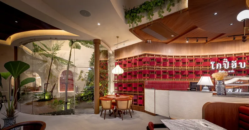 Interior dining area with glazed courtyard garden and potted palms beside timber columns