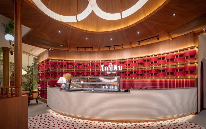Curved service counter with ribbed white cladding beneath a wood-paneled dome ceiling with circular skylight