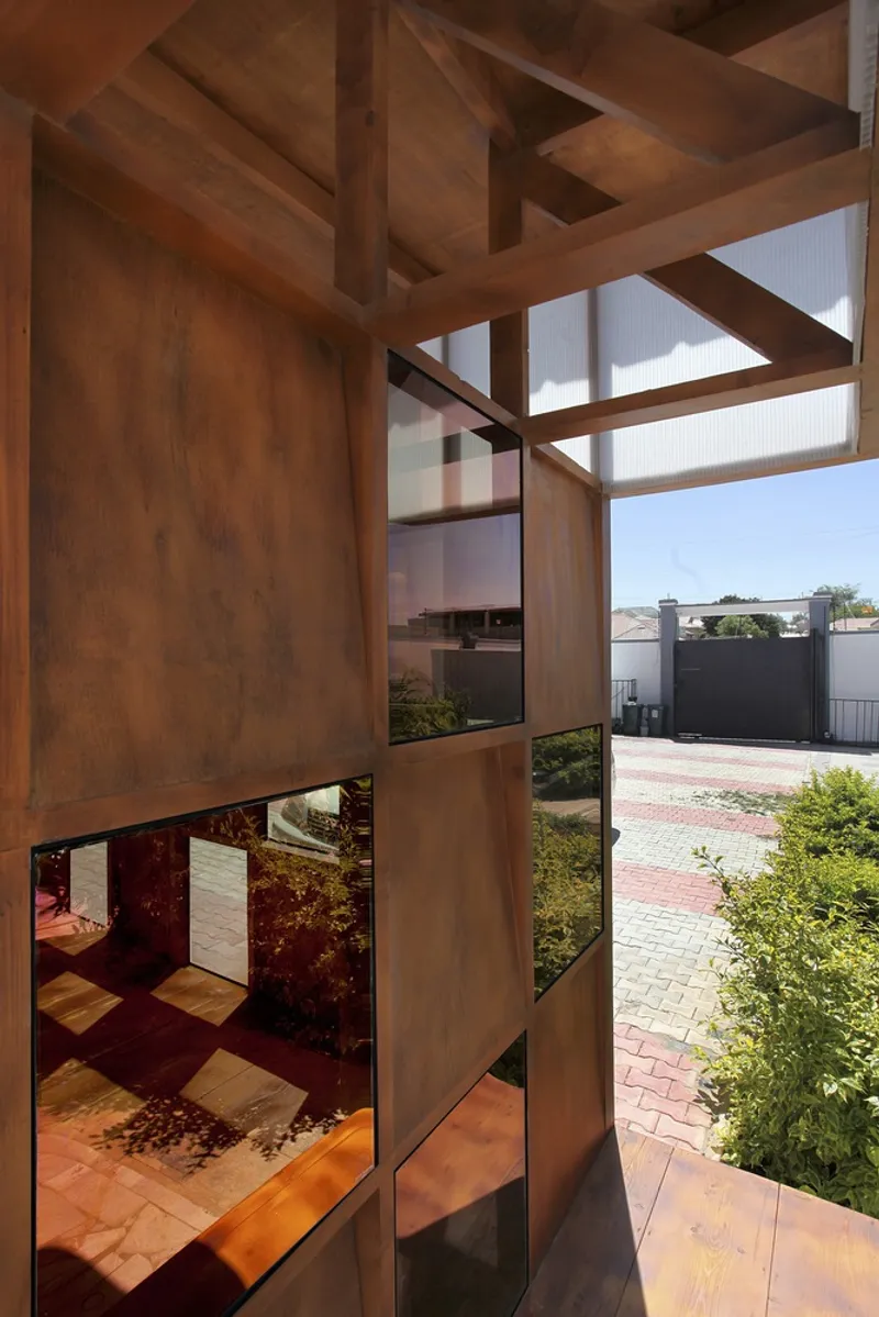 Timber frame structure with glazed and solid panels overlooking garden and paved pathway below