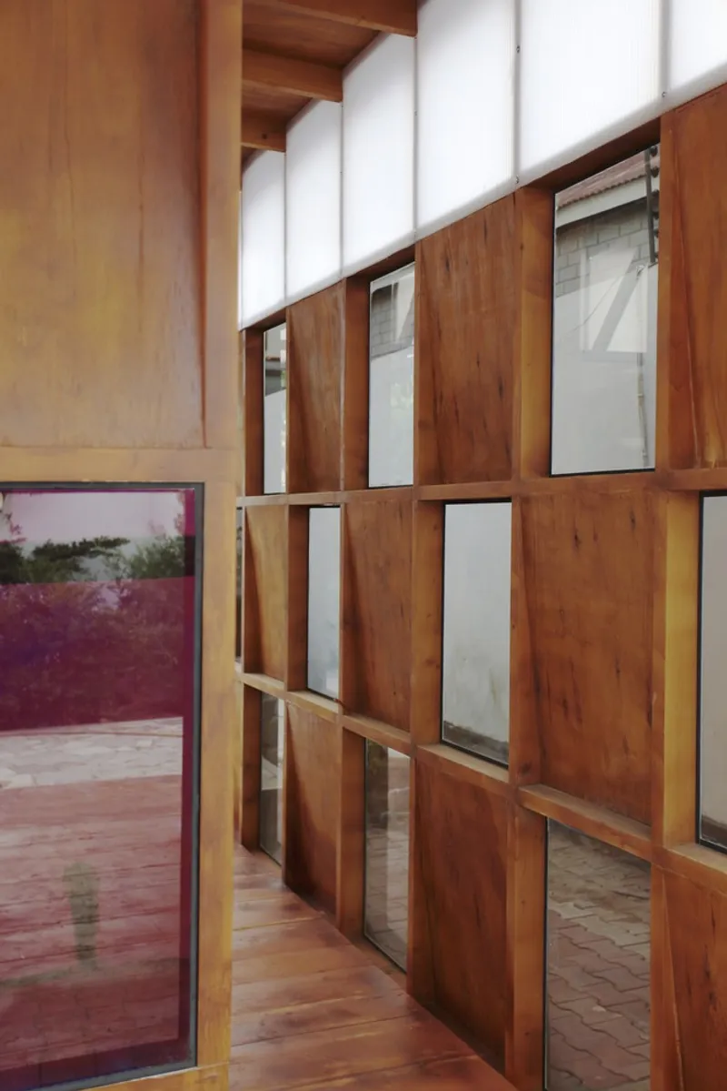 Corridor with timber and glass partition wall and translucent clerestory panels above exposed beam ceiling
