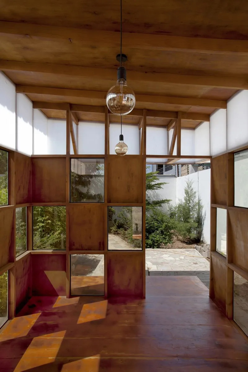 Interior with timber framed glazing looking onto courtyard garden with two spherical glass pendant lights
