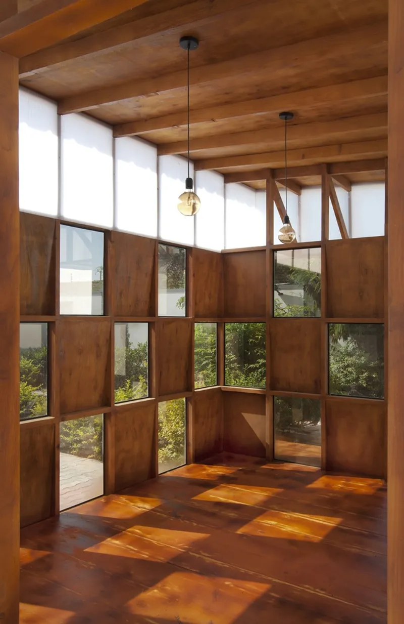 Interior corner with timber ceiling and chequered wood and glass wall panels overlooking garden plantings