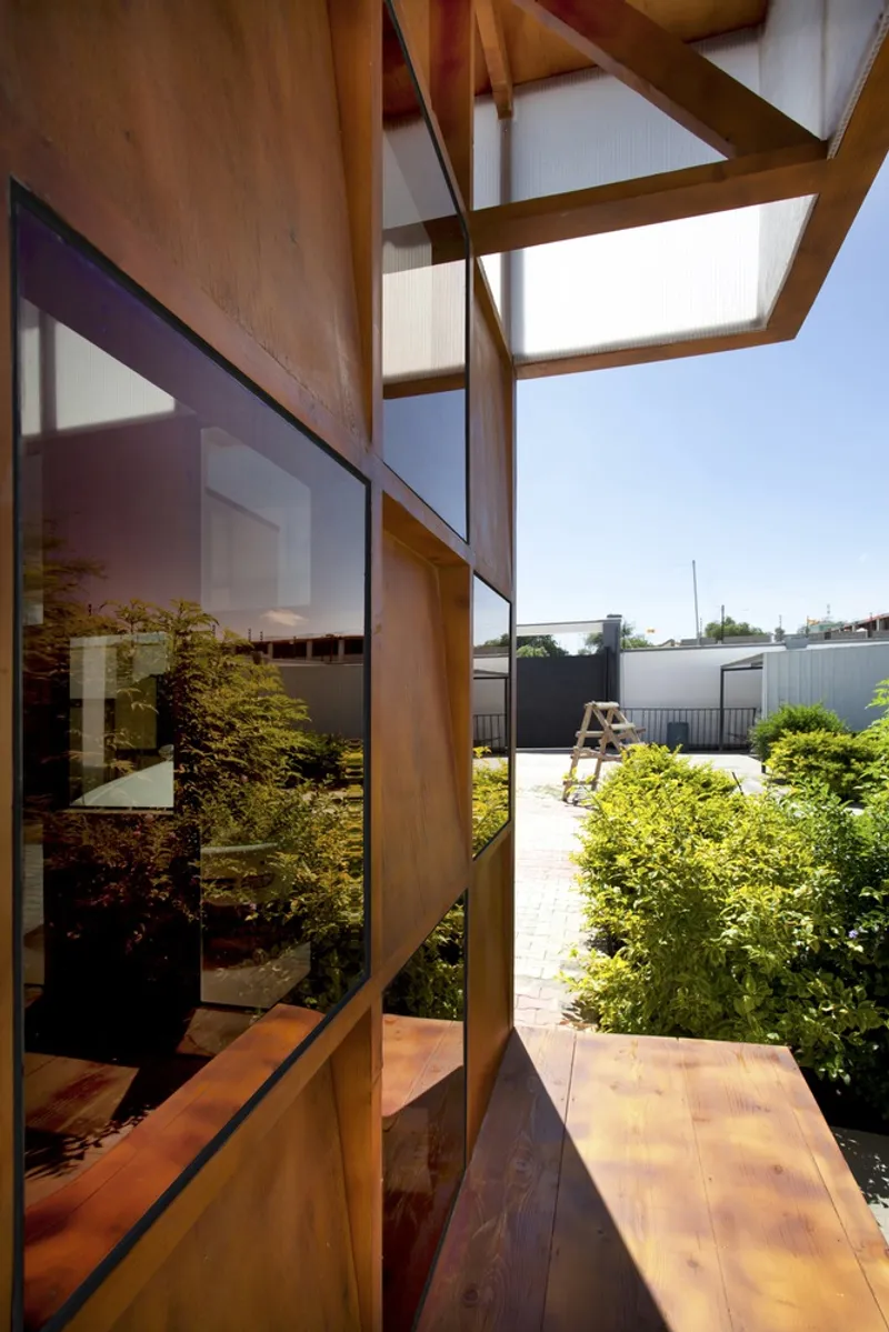 View from interior window seat through timber frame to landscaped courtyard under bright midday sun