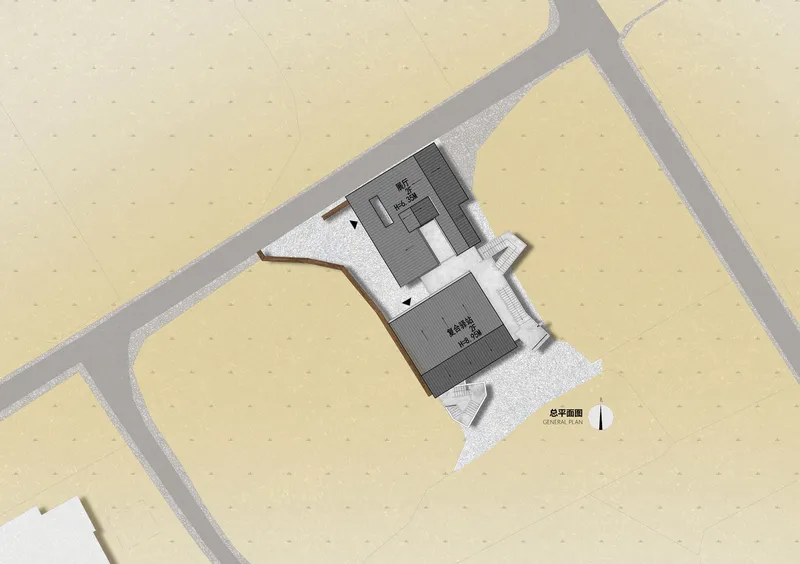 Site plan drawing showing two connected rectangular volumes surrounded by pathways and gravel surfaces