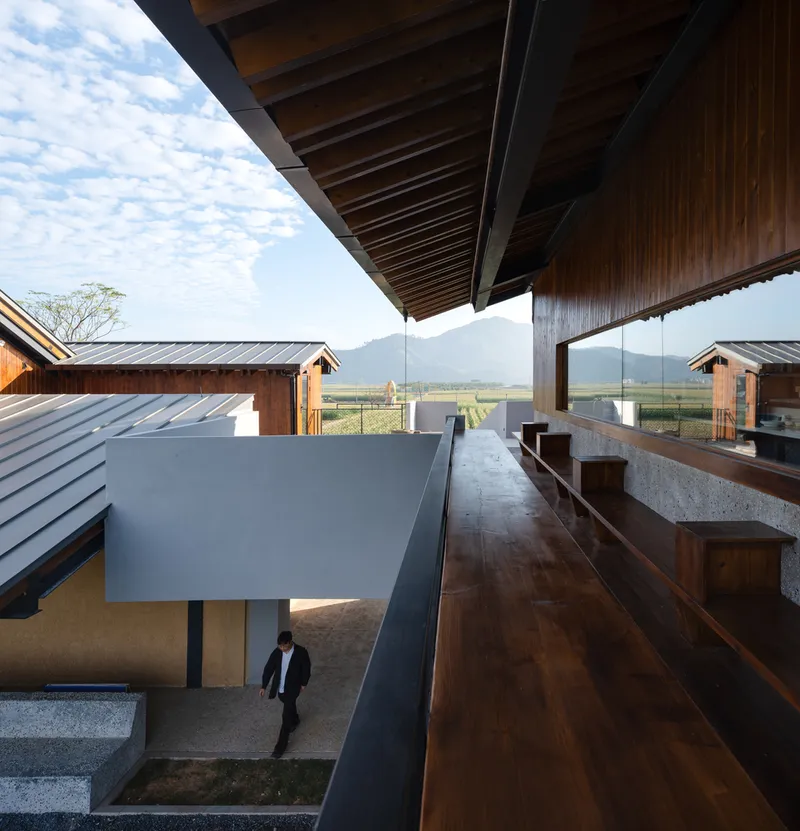 Upper terrace with timber bench seating and exposed rafters overlooking the courtyard and fields