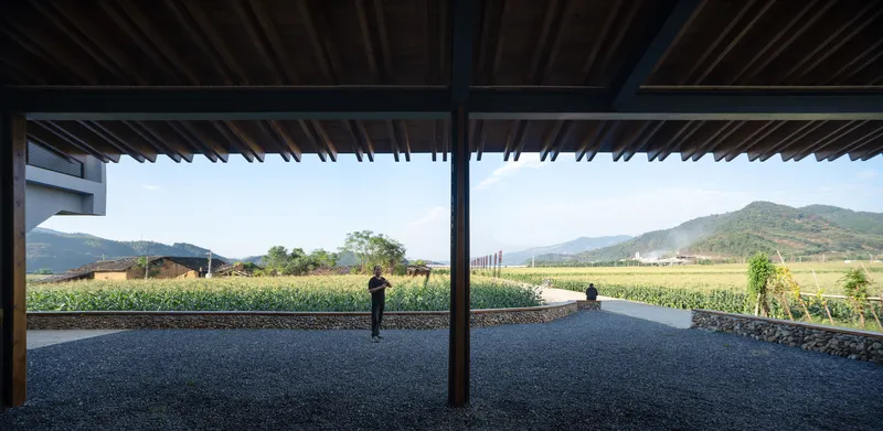 Covered terrace with exposed timber rafters framing a view of agricultural fields and distant mountains