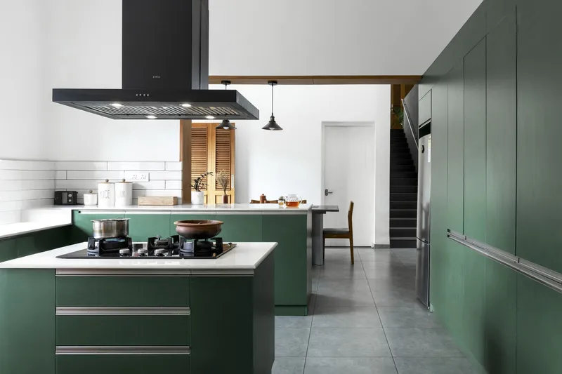 Kitchen with green cabinetry and white subway tile backsplash beside a timber-framed doorway