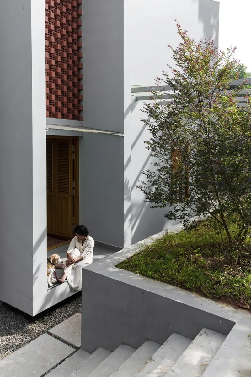 Concrete stairway descending to a courtyard with a person and dog near the timber entry door