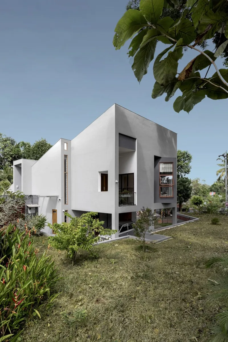 White rendered volumes on pilotis set in a sloping garden under banana tree foliage